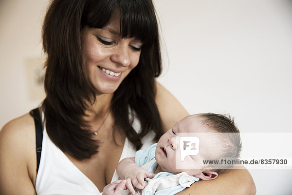 Lächelnde junge Mutter mit ihrem neugeborenen Sohn