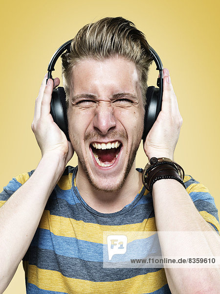 Portrait of screaming young man with headphones  studio shot