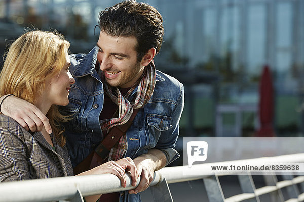 Germany,  Dusseldorf,  Young couple embracing,  leaning on railing