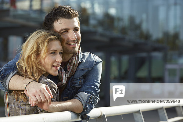 Germany  Dusseldorf  Young couple embracing  leaning on railing