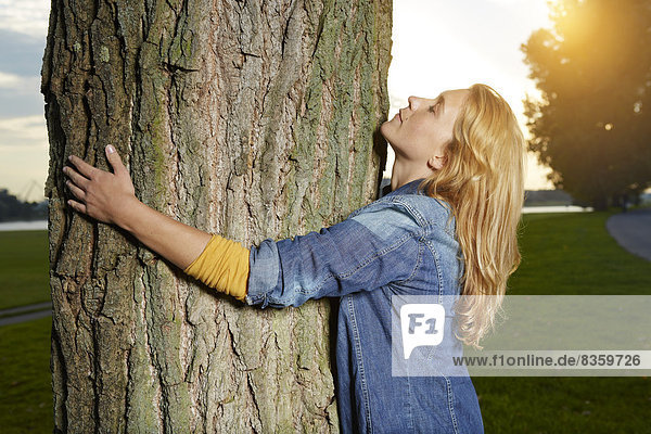 Young woman hugging tree