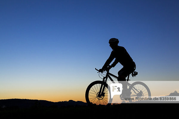 Germany  Winterbach  cyclist on a mountain bike at sunset