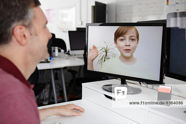 Man sitting at desk having video call with son