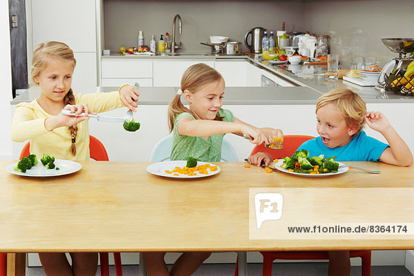 Mädchen schaufeln Gemüse auf den Teller des Jungen