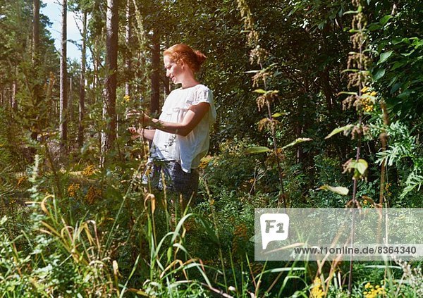 Woman standing in forest  looking at plants