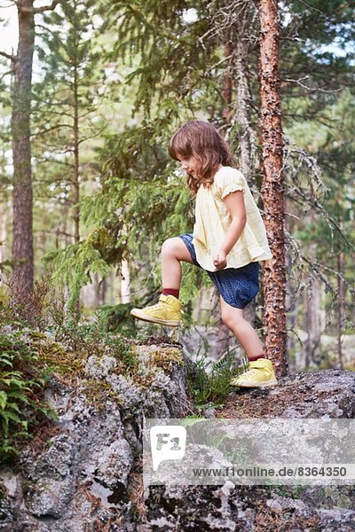 Girl climbing over rocks in forest