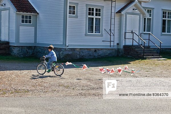 Junge reitend Fahrrad ziehendes Fähnchen
