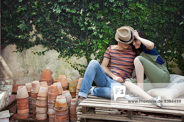 Couple sitting on wooden palettes  man wearing straw hat