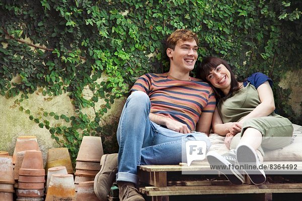 Couple sitting on wooden palettes with plant pots