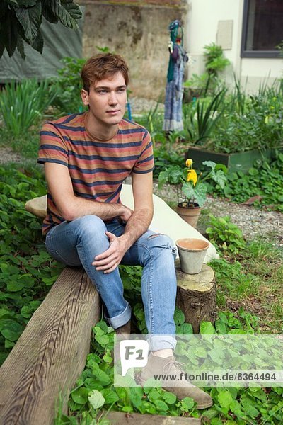 Junger Mann sitzend am Gemüsegarten