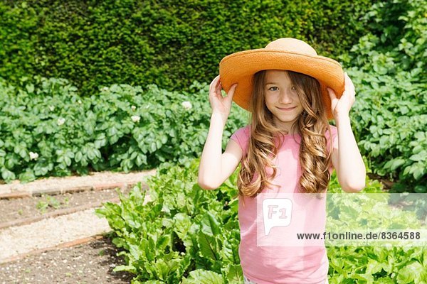 Mädchen mit Strohhut im Garten