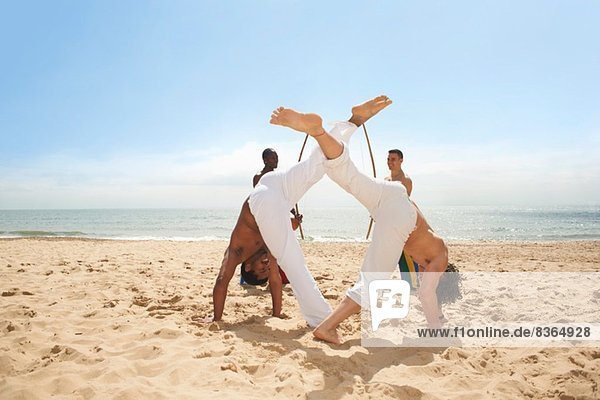 Men doing capoeira on beach