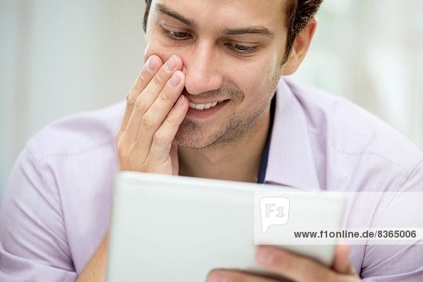 Young man looking at message on digital tablet