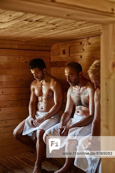 Drei Männer sitzen in der Sauna mit dem Kopf nach unten.