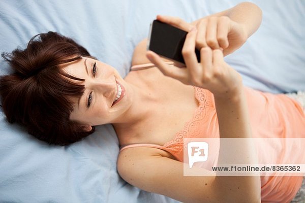 Overhead-Ansicht der jungen Frau auf dem Bett mit Selbstporträt
