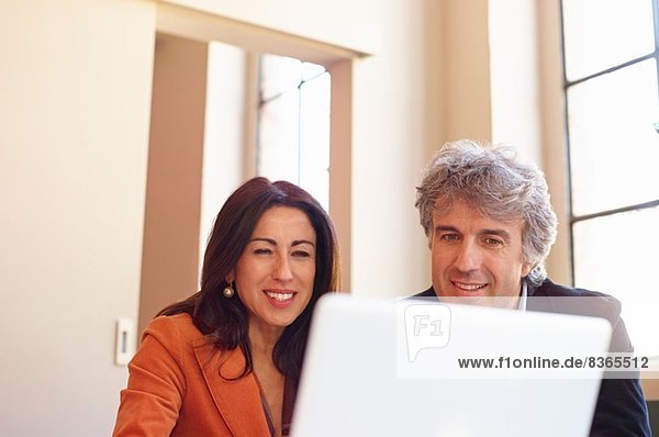 Mature businessman and woman using laptop