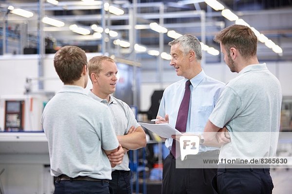 Workers and manager meeting in engineering warehouse