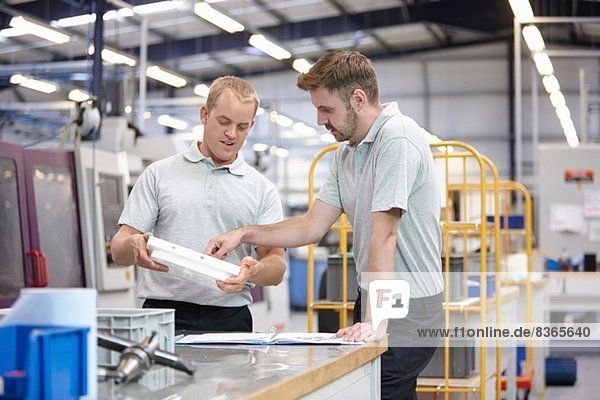 Arbeiter diskutieren über Bauteil in der Maschinenfabrik