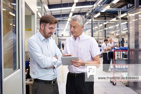 Manager and worker looking at digital tablet in engineering factory