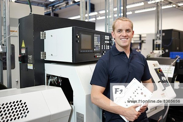 Portrait of engineer holding component in engineering factory