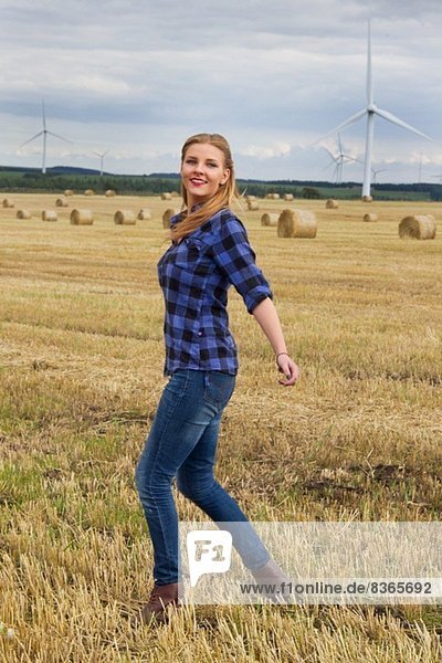 Young woman walking in harvested field