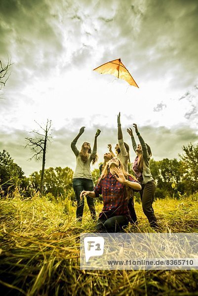 Fünf junge Frauen beim Drachenfliegen im Buschland