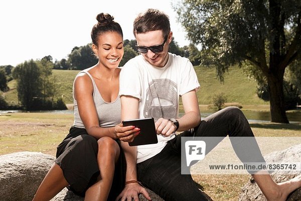 Junges Paar mit digitalem Tablett im Park
