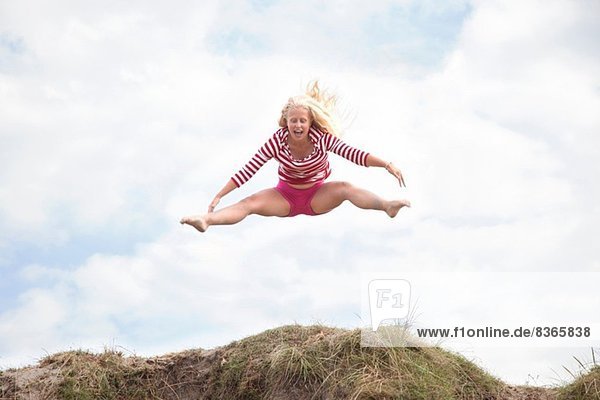 Teenager-Mädchen springt in der Luft mit ausgestreckten Beinen,  Wales,  UK