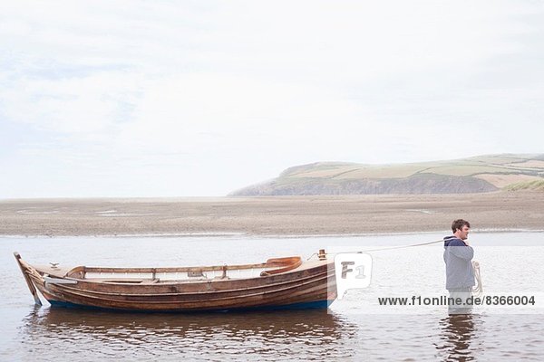 Mann zieht Ruderboot durchs Wasser  Wales  UK
