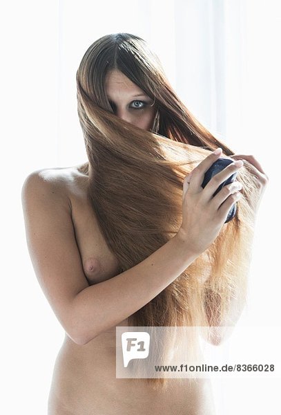 Junge Frau bürstet lange braune Haare