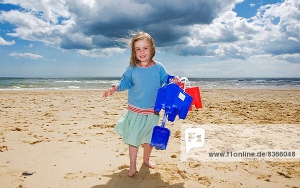 Young girl holding bucket and spade on beach  Walberswick  Suffolk  England  UK