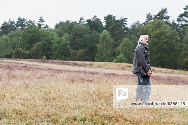 Senior man standing in meadow