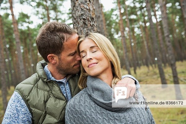 Mittleres erwachsenes Paar  das sich im Wald umarmt