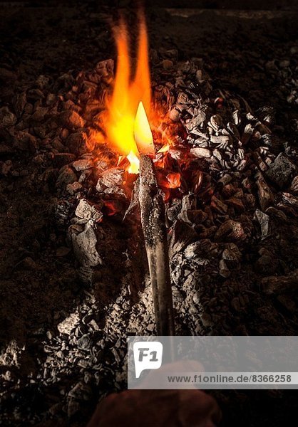 Schmied hält Metallmesser im Ofen
