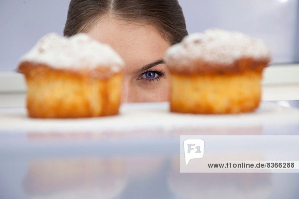 Junge Frau schaut frisch gebackene Kuchen an