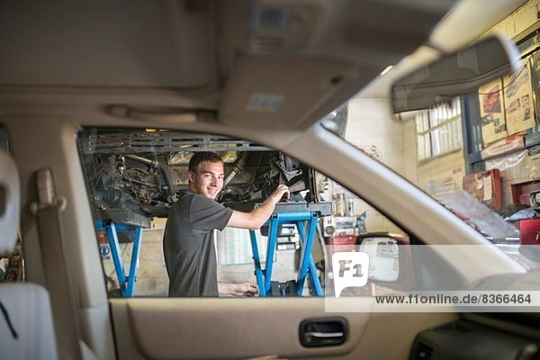 Mechanic smiling toward camera through car window