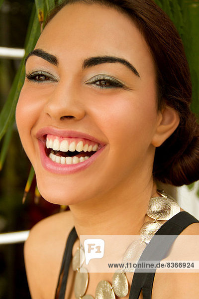 Porträt einer jungen Frau  lächelnd mit kreisförmiger Halskette