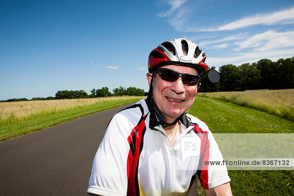 Senior man riding bicycle through countryside