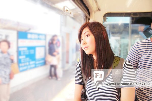 Junge Frau im Zug  durchs Fenster schauend
