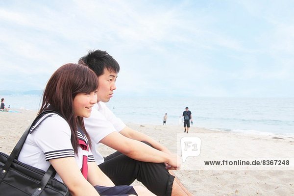 Young couple sitting on sandy beach