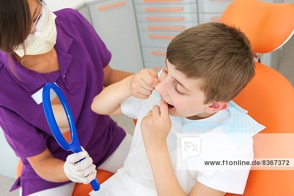 Dentalhygieniker hält Handspiegel  während der Patient flosst