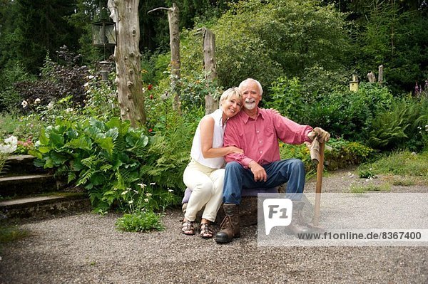 Porträt eines älteren Paares  das im Garten sitzt