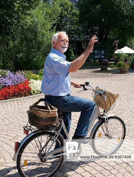 Älterer Mann mit dem Fahrrad durch den Park