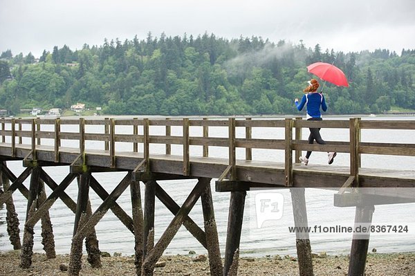 Teenager Mädchen mit Regenschirm am Pier  Bainbridge Island  Washington  USA