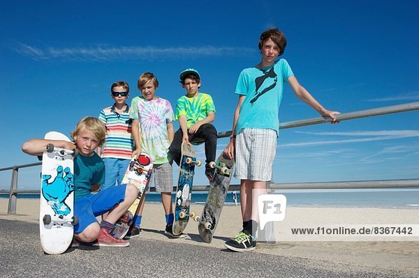 Portrait von fünf Jungen mit Skateboards an der Küste