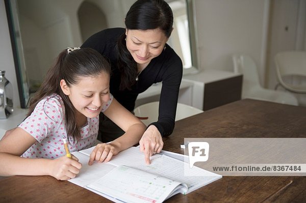 Mother helping teenage daughter with homework
