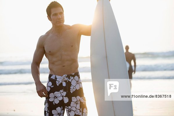 Man holding surfboard on beach