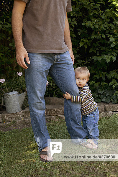 A Young Boys Holds Onto His Father's Leg Pacifica  California  United States Of America