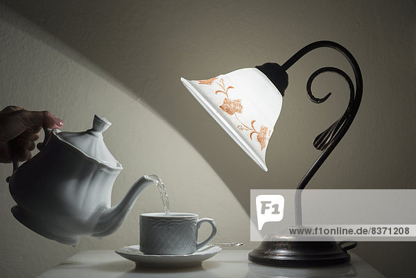 A Lamp Shining On A Hand Holding A Teapot Pouring Tea Into A Teacup Sestri Levante  Emilia-Romagna  Italy