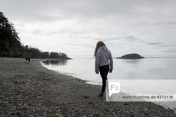 A Young Woman Walks On A Rocky Beach In Deception Pass State Park Oak Harbor  Washington  United States Of America